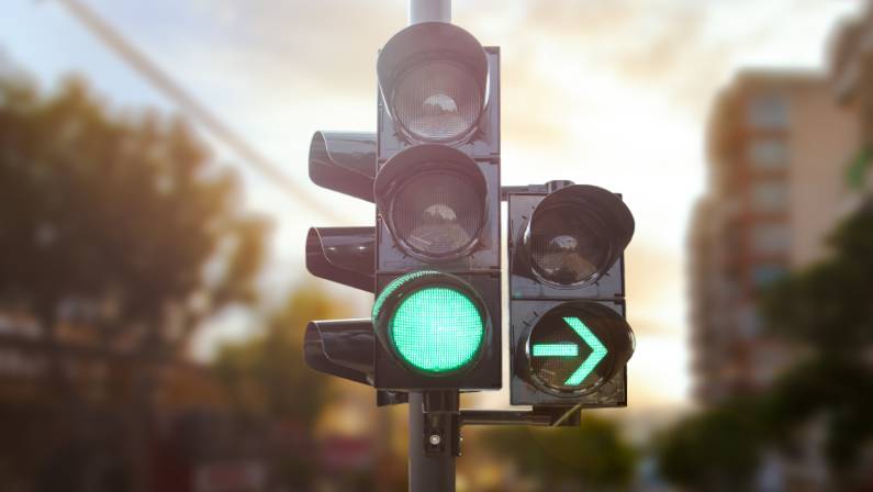 Green traffic light with green arrow light up in city